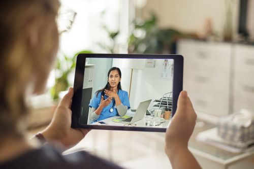 A woman holding a tablet in a conference call.